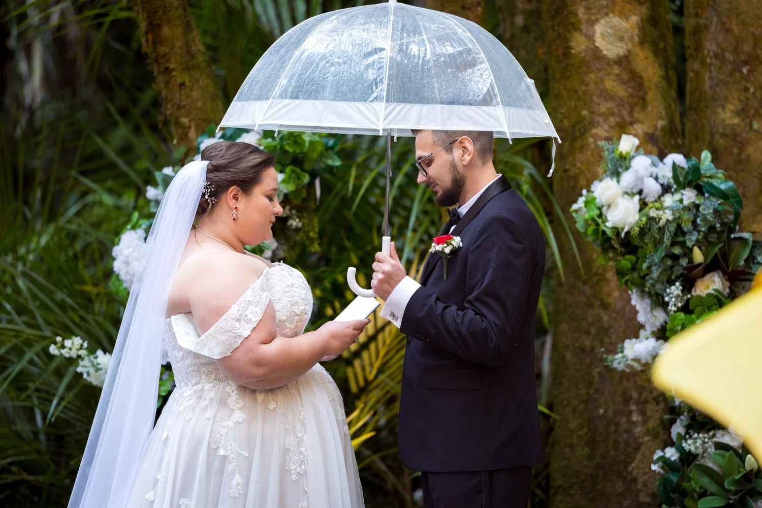 Rebecca and Nick exchange vows under a clear umbrella in the rain