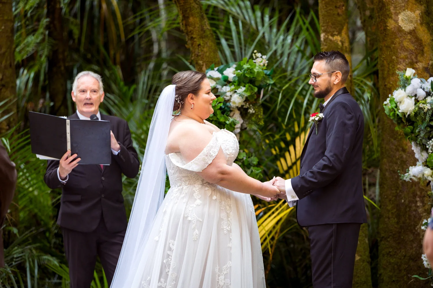Rebecca and Nick hold hands as the celebrant reads