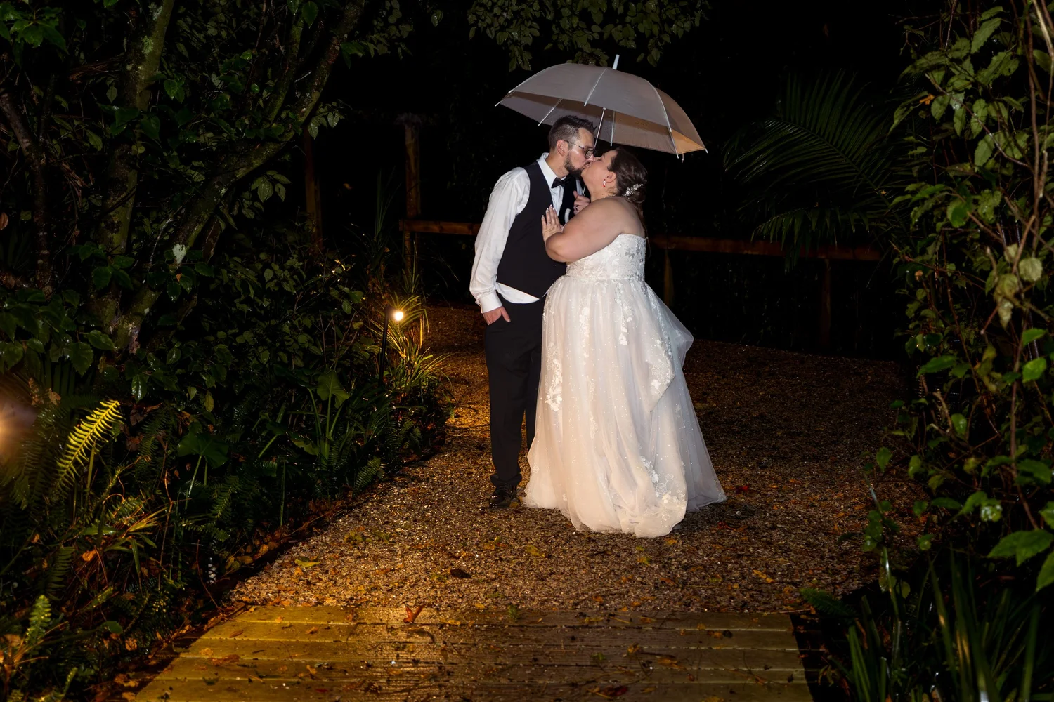 Rebecca and Nick kiss under an umbrella at night