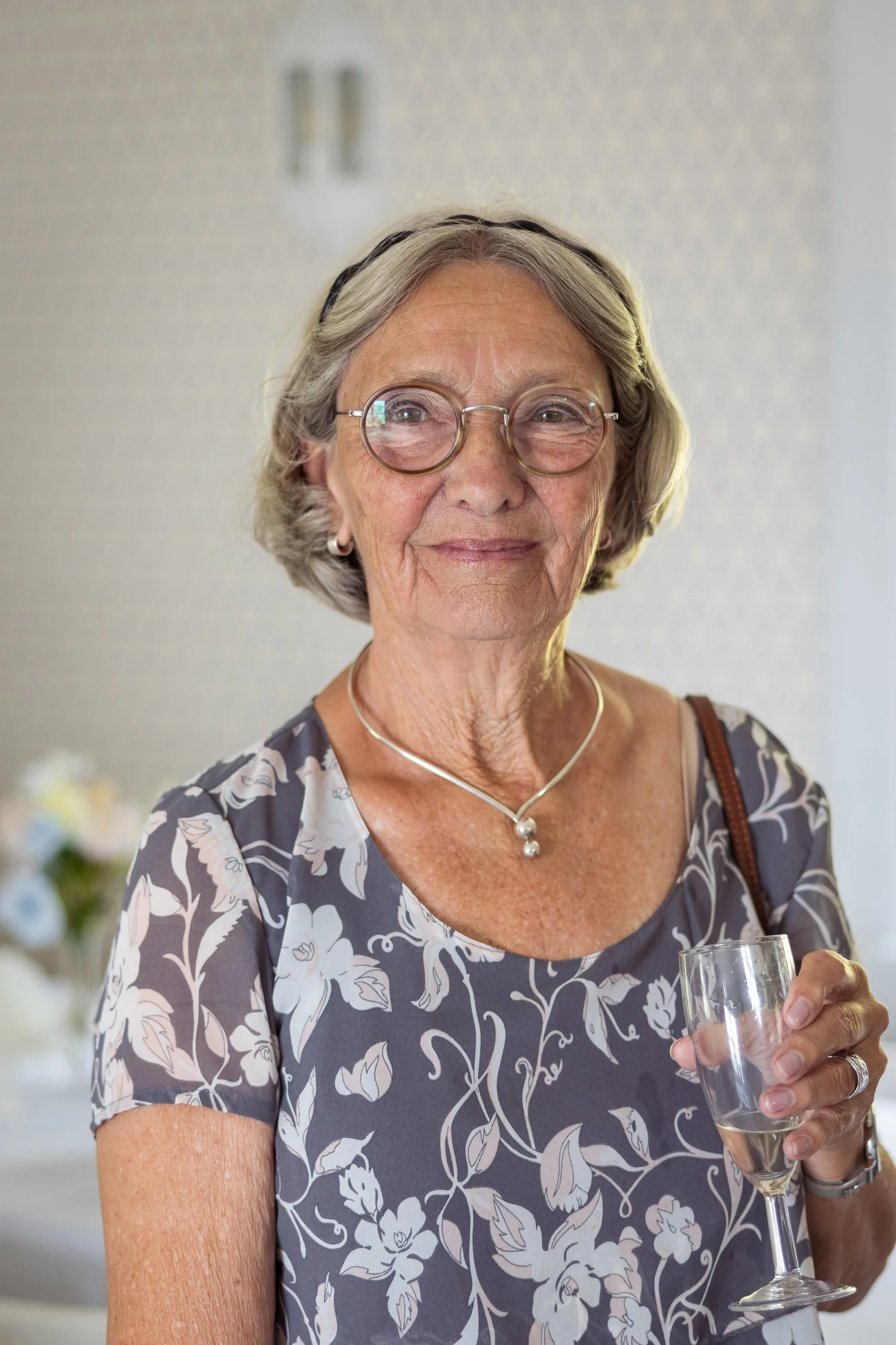 A smiling guest in glasses holding a glass of wine