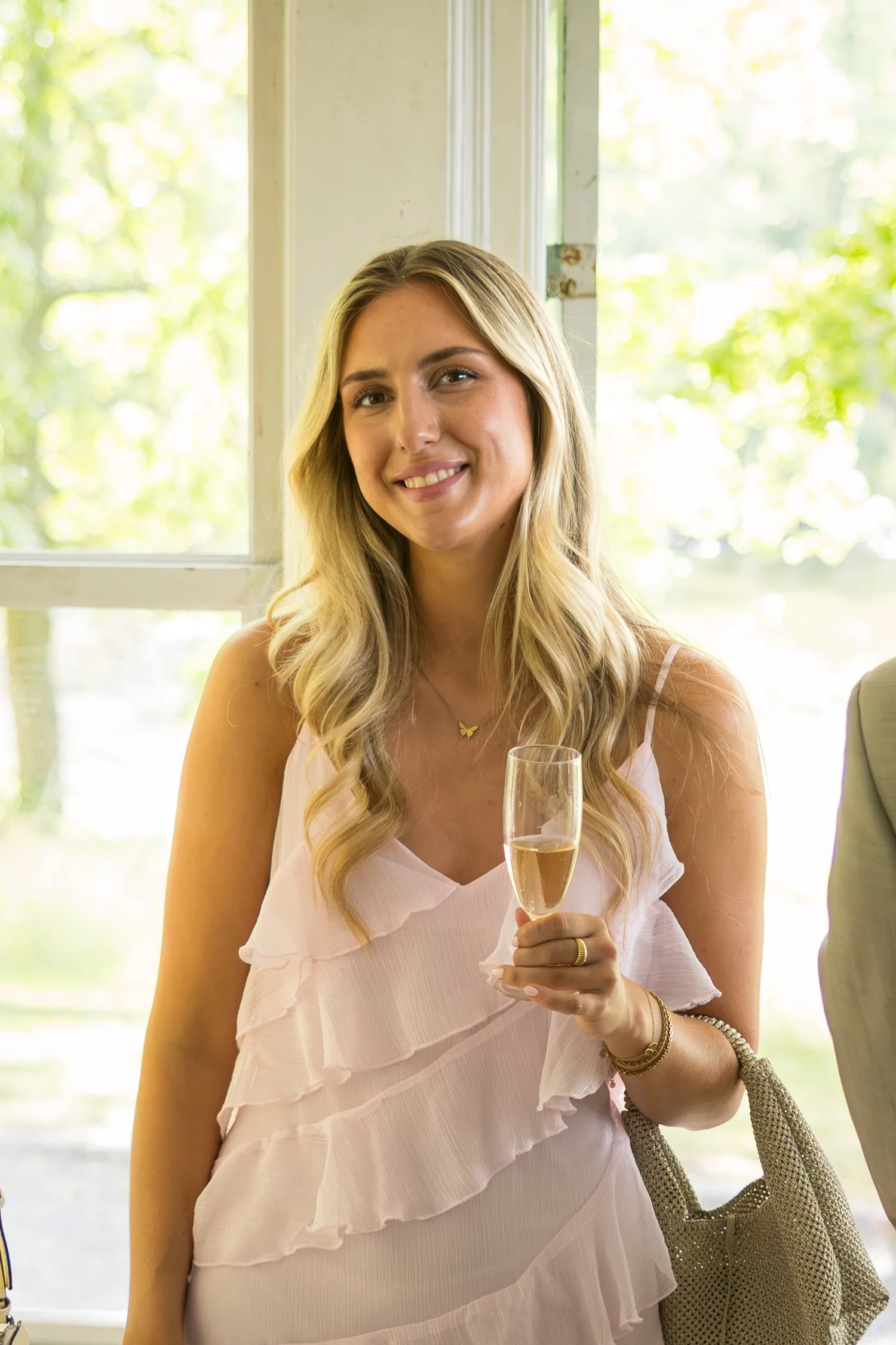 A guest in a pink ruffled dress holds a glass of champagne