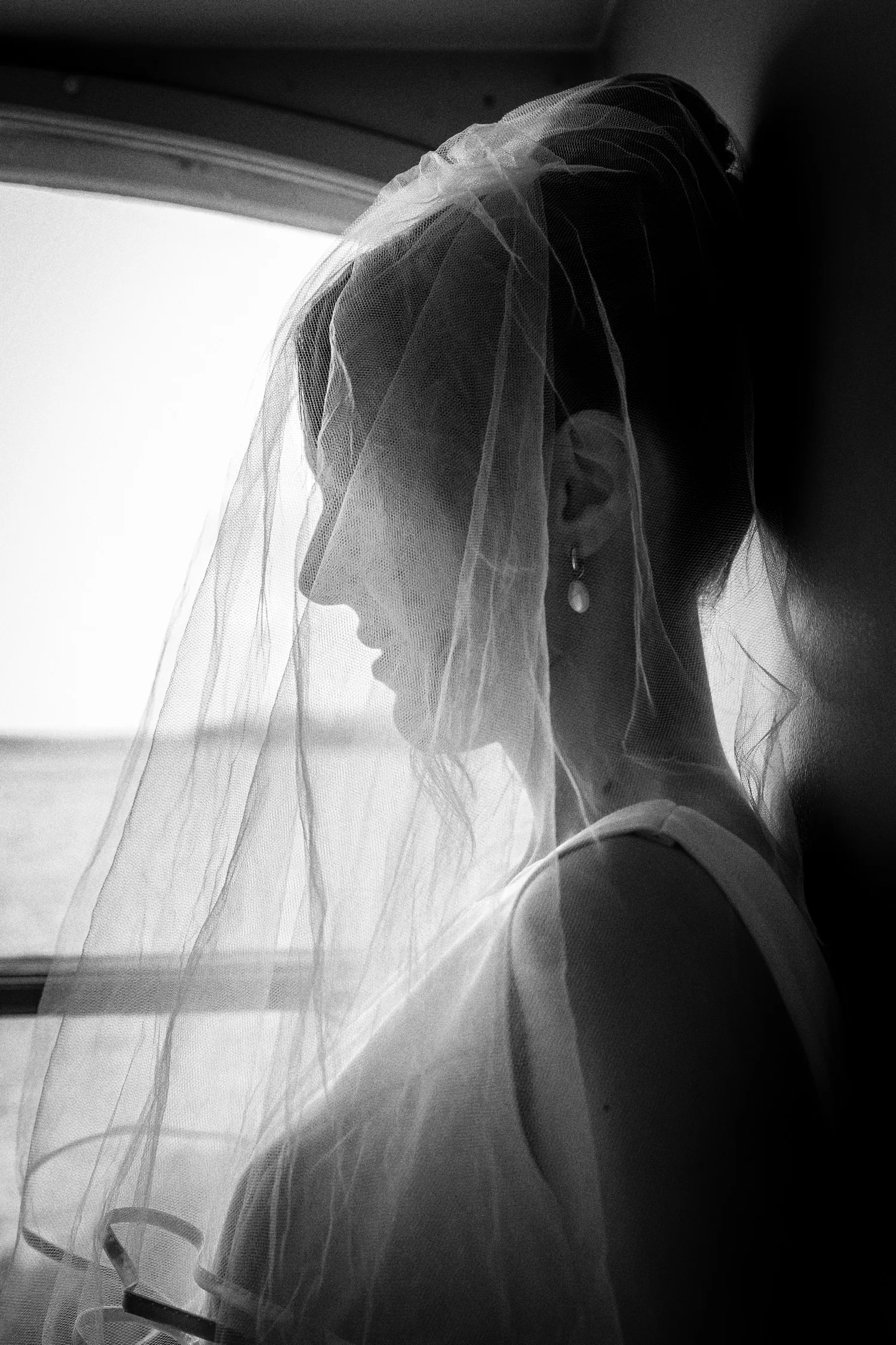 Black and white photo of Sofia in her veil by a window