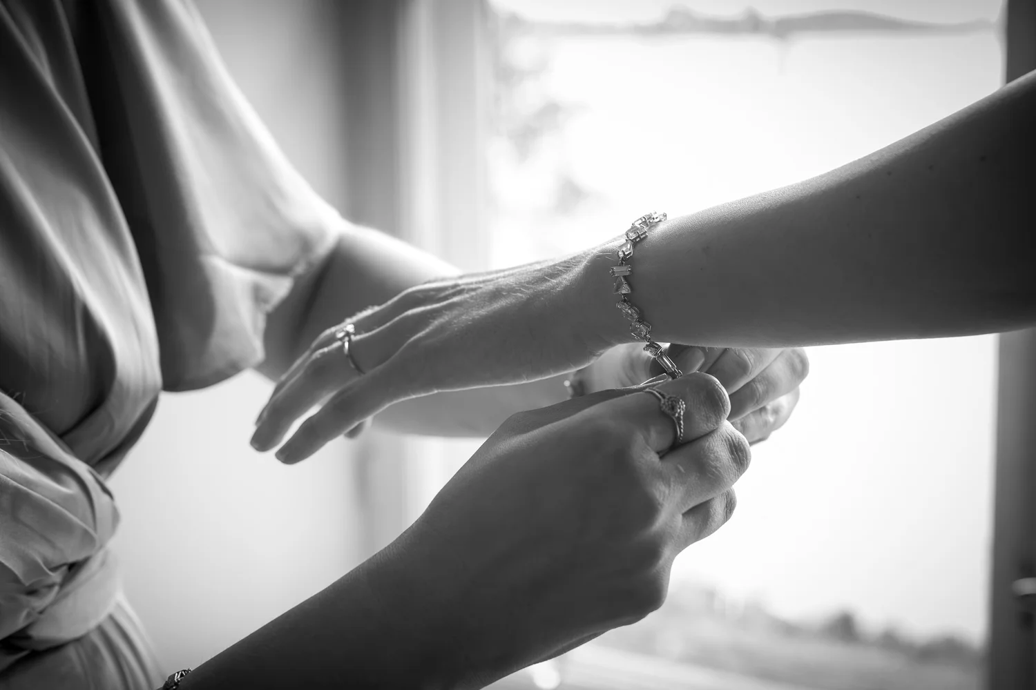 Black and white close-up of a bracelet being fastened on Sofia's wrist
