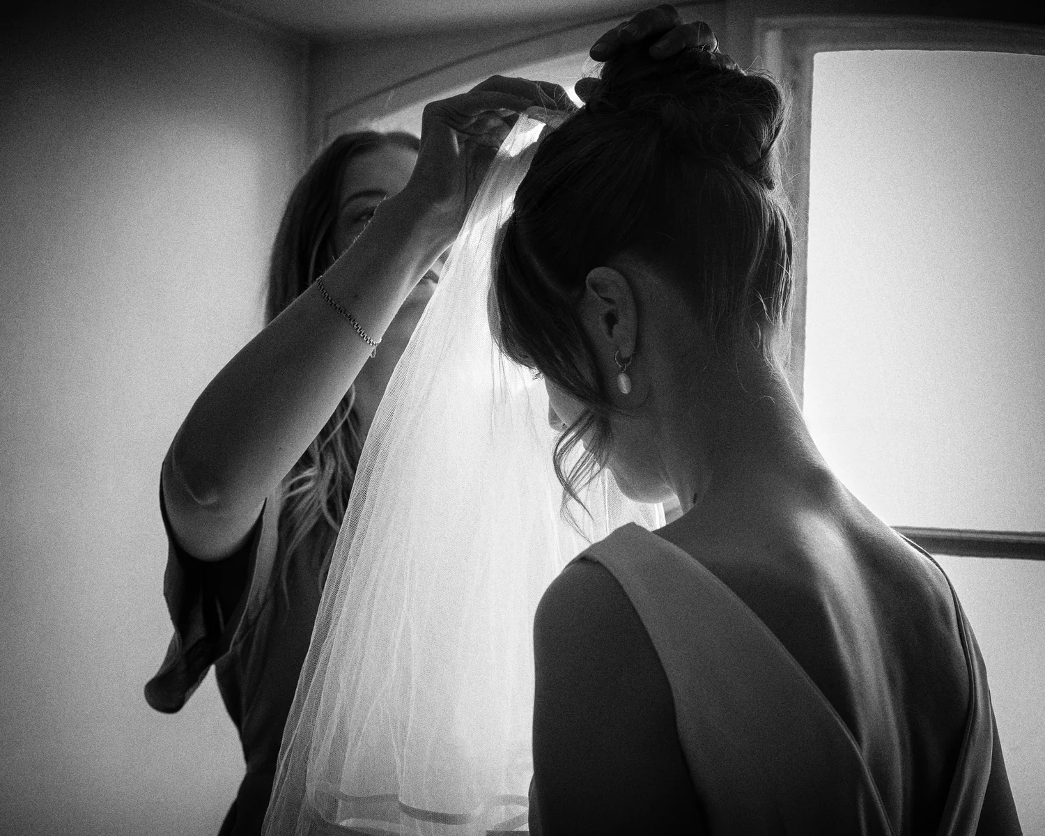 Black and white photo of Sofia's veil being placed in her hair