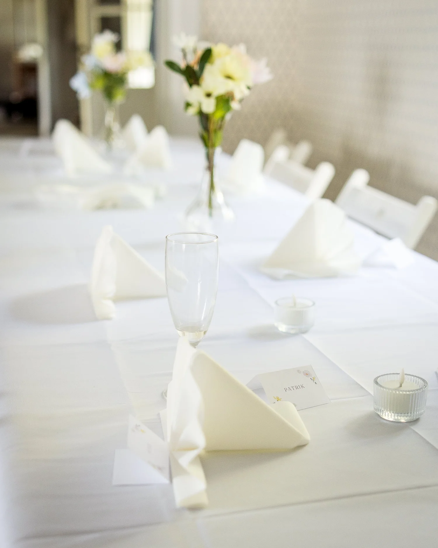 White table settings with small vases of white flowers