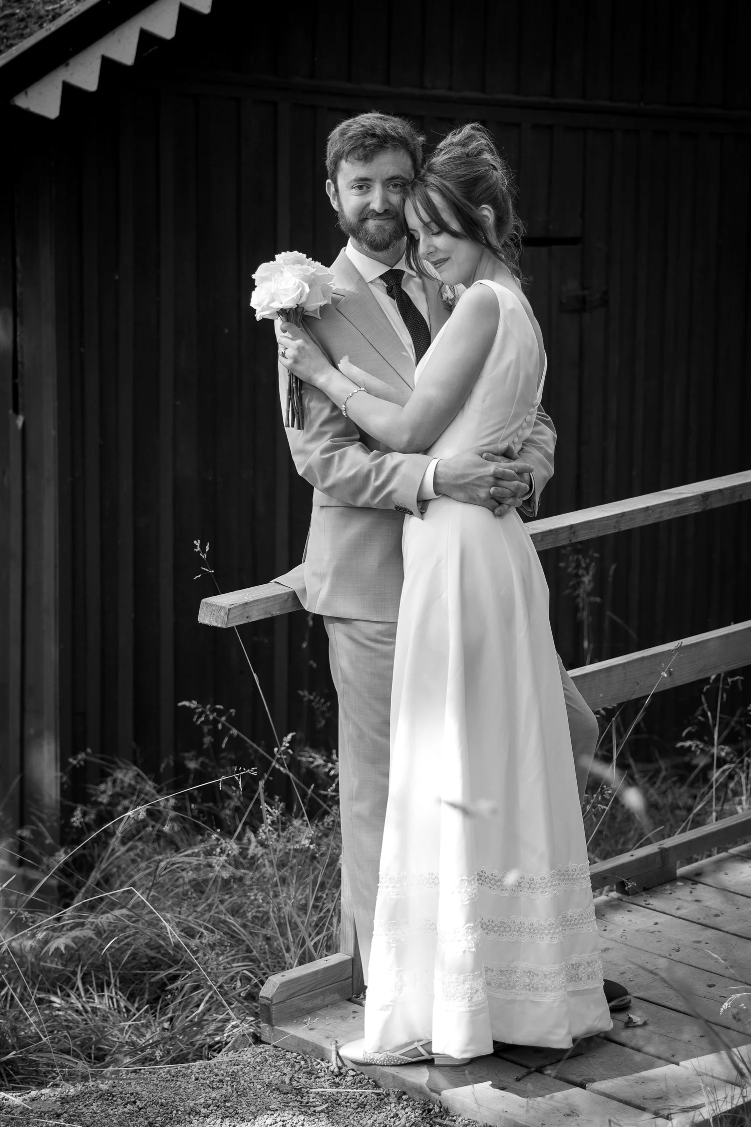 Black and white photo of Sofia and John embracing on a wooden step