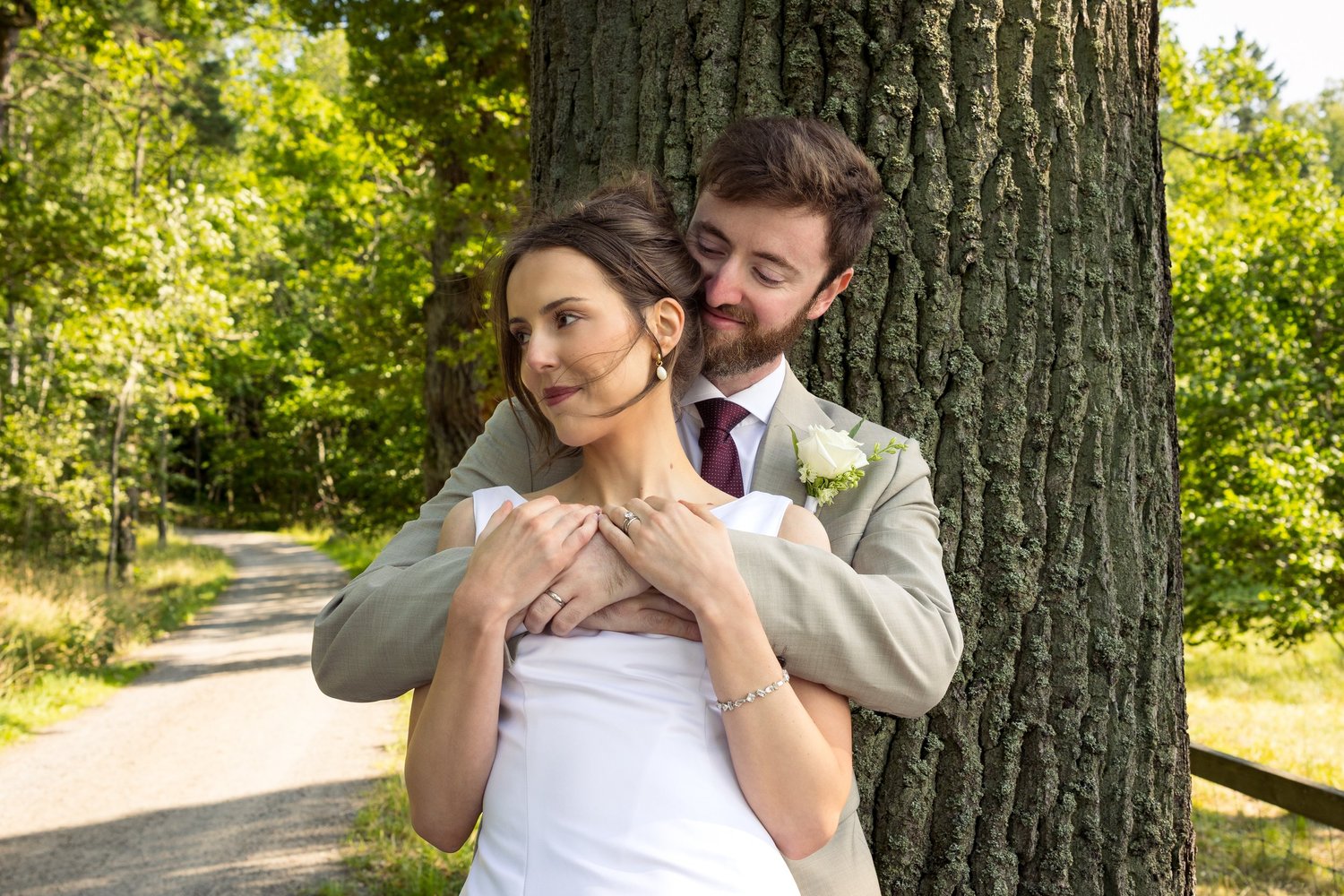 John hugs Sofia from behind against a large tree