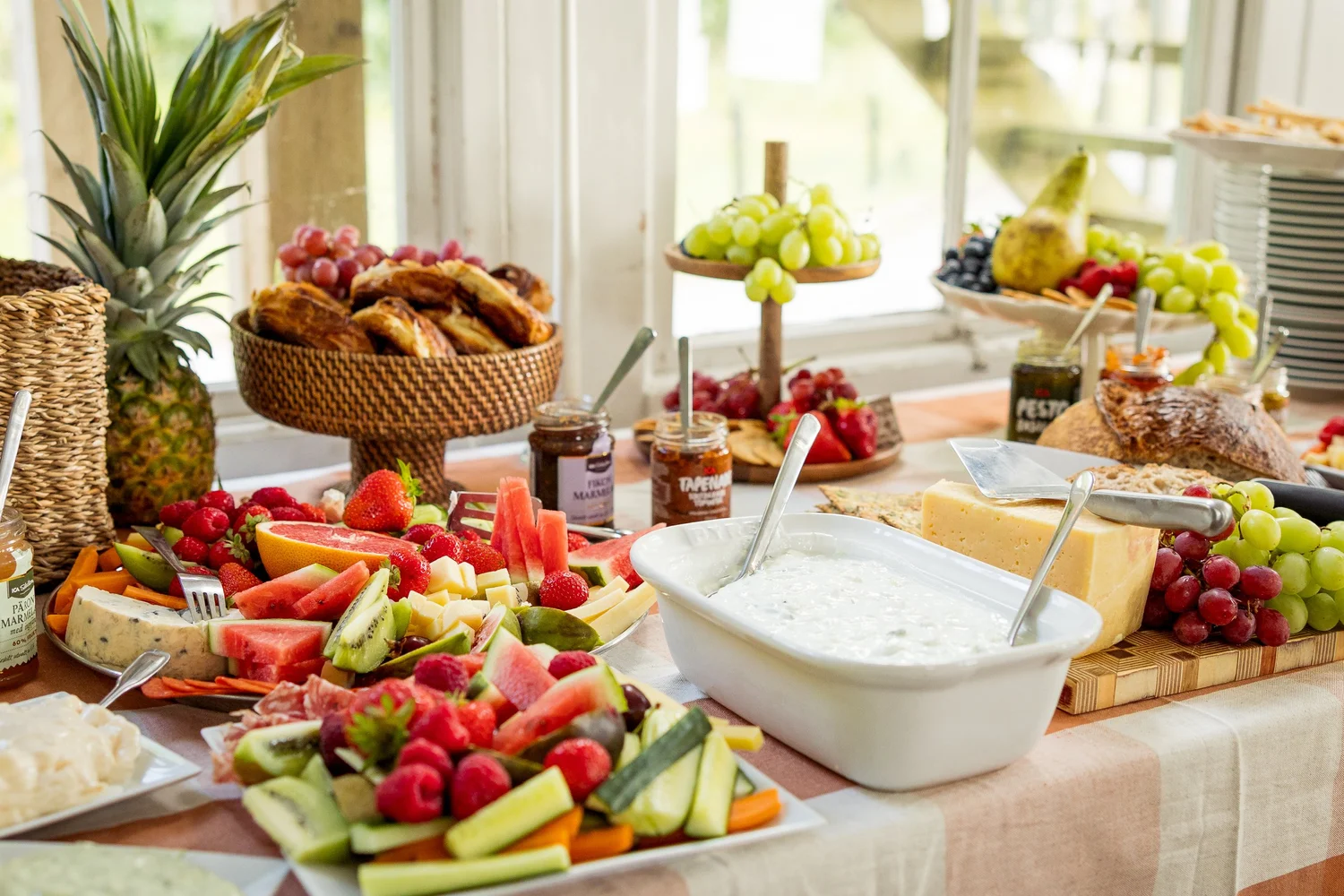 A colourful table of fruit, cheese and snacks