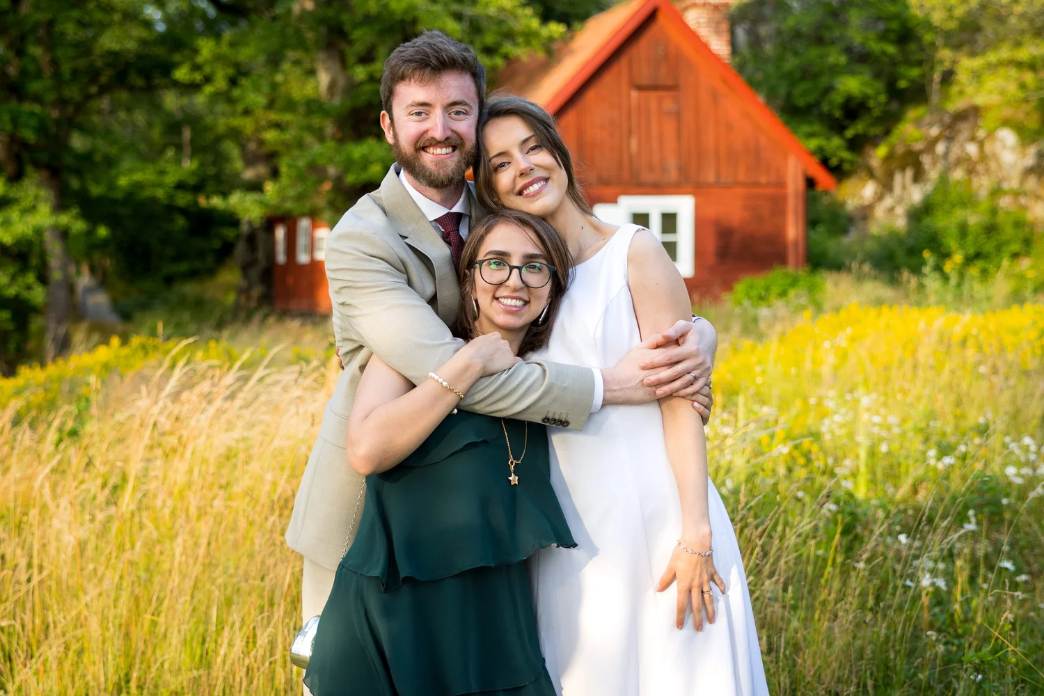 Sofia and John hug a guest in the meadow