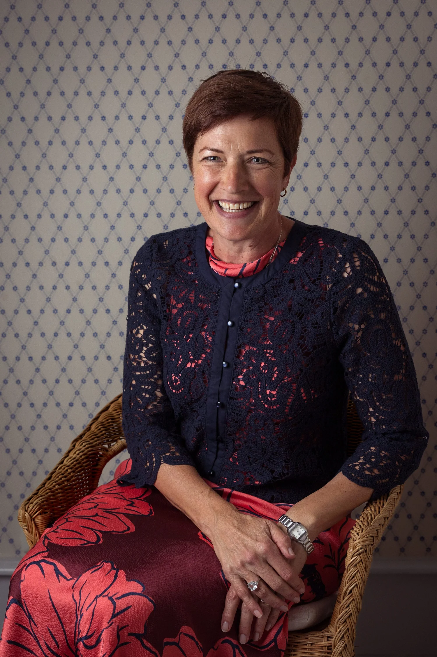 A smiling guest in a navy lace top seated for a portrait