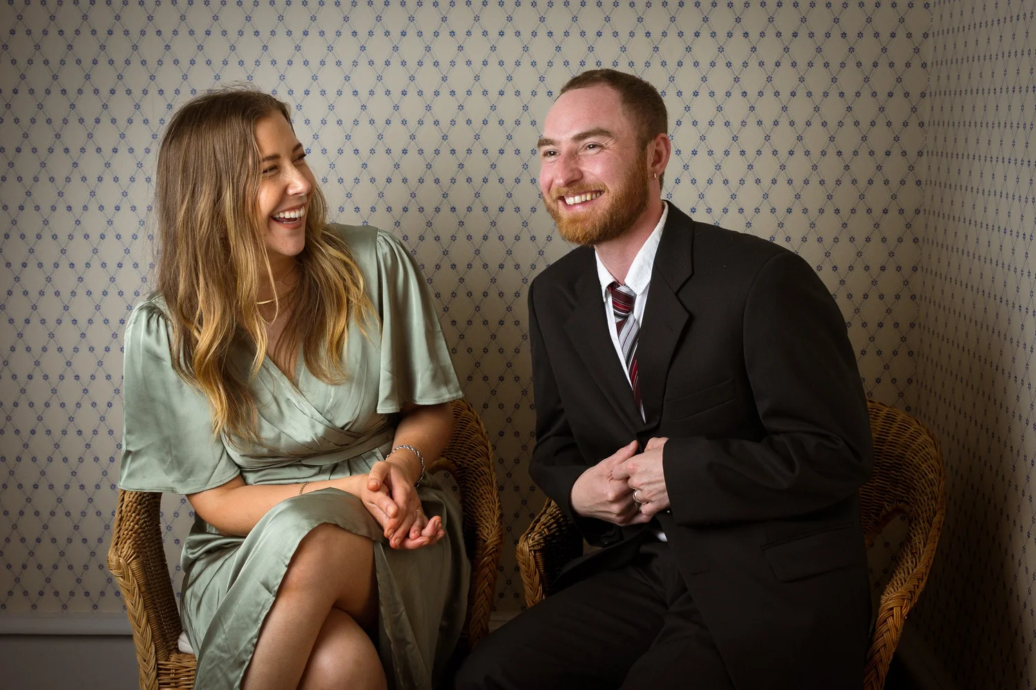 Two guests laugh together in wicker chairs
