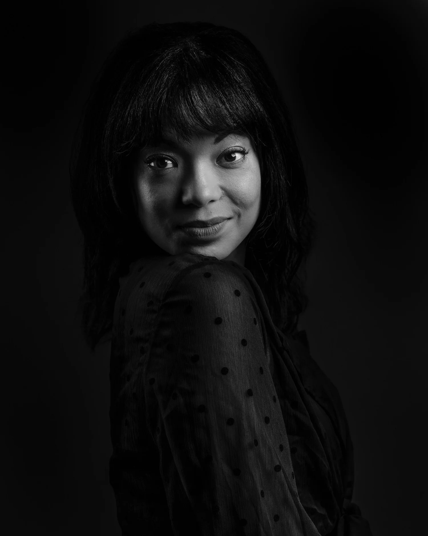 Black and white portrait of a smiling woman in low light