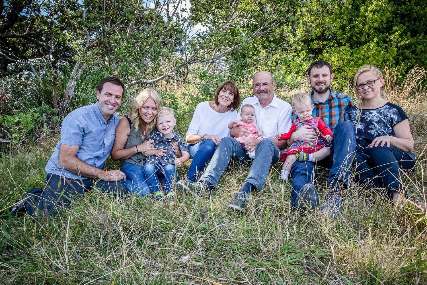 A family of three generations sitting together in long grass