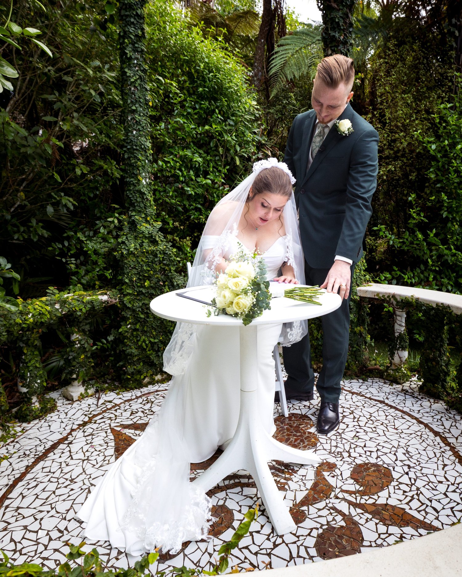 A couple sign the register on a mosaic courtyard