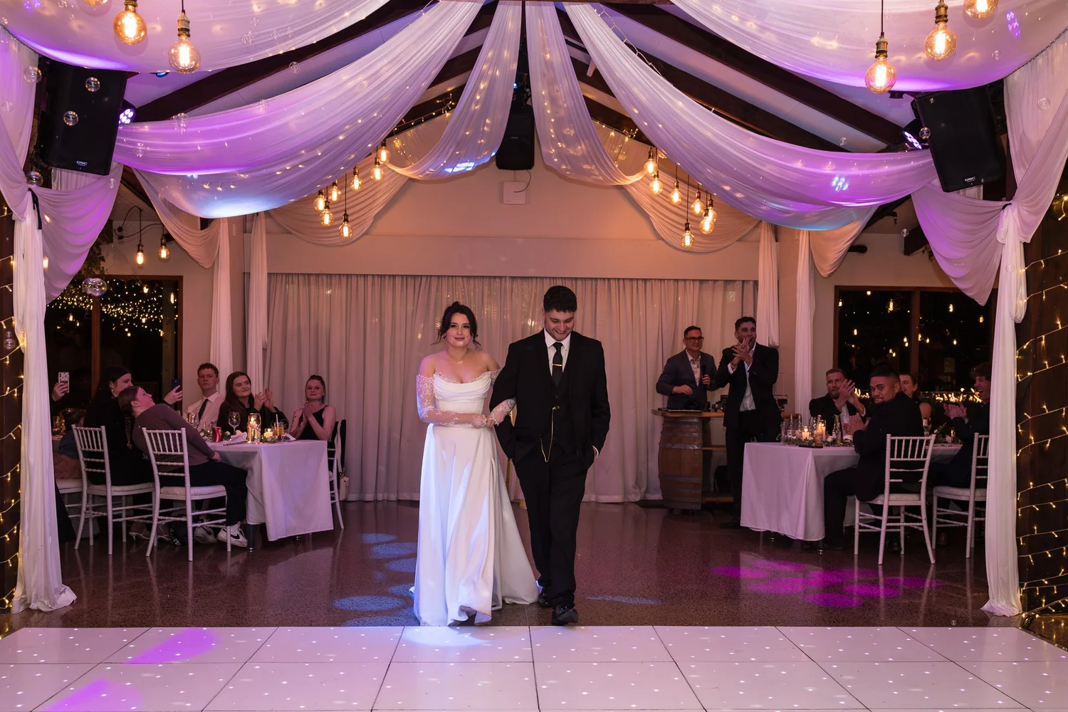 A couple's first dance under pink lights and draped fabric