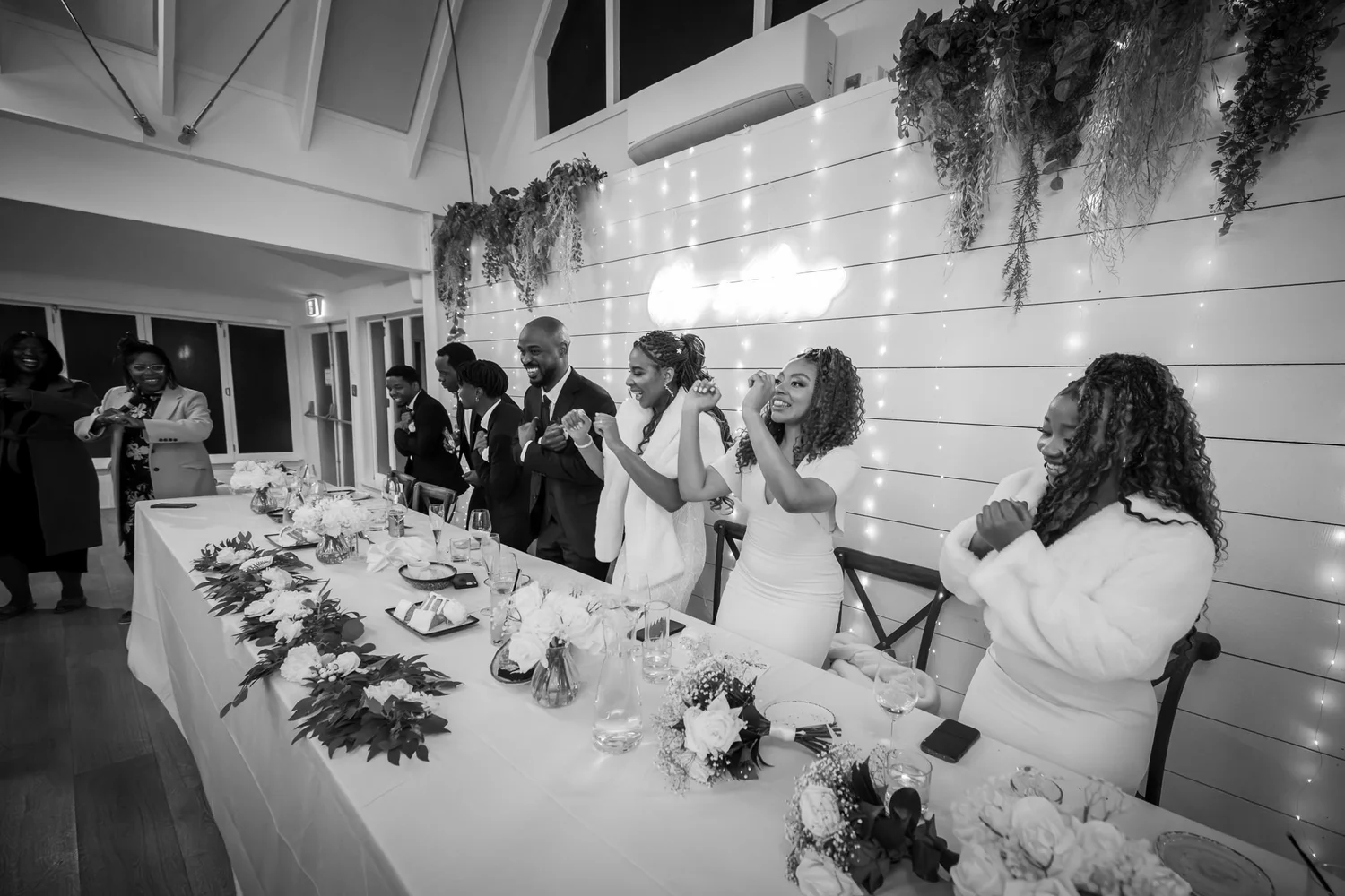 Black and white photo of guests celebrating at the head table