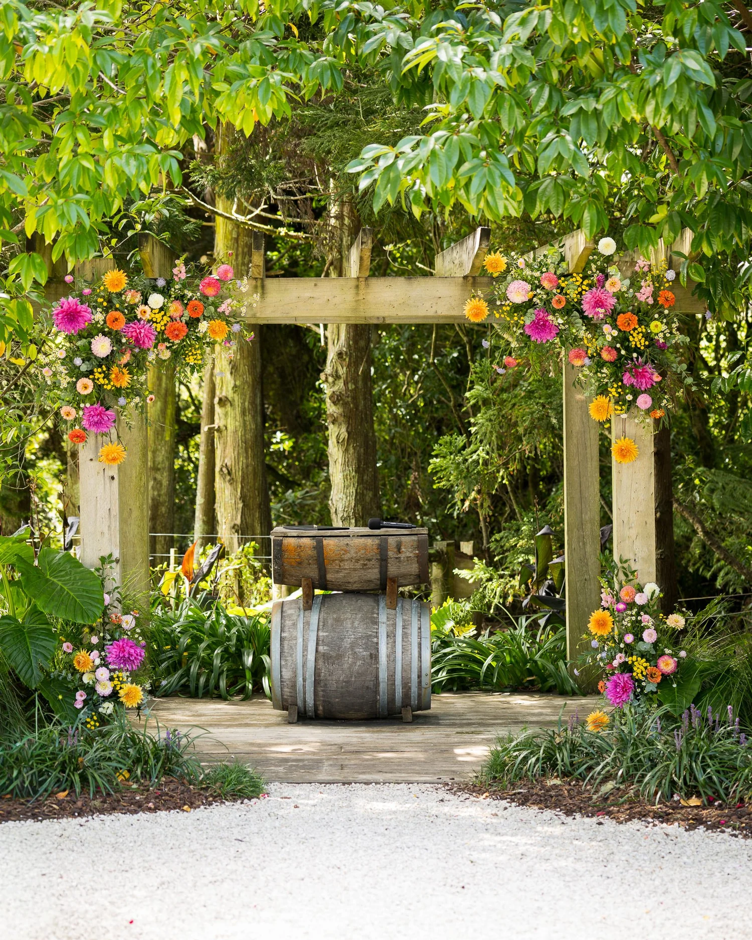 The ceremony arch decorated with colourful flowers and a wine barrel