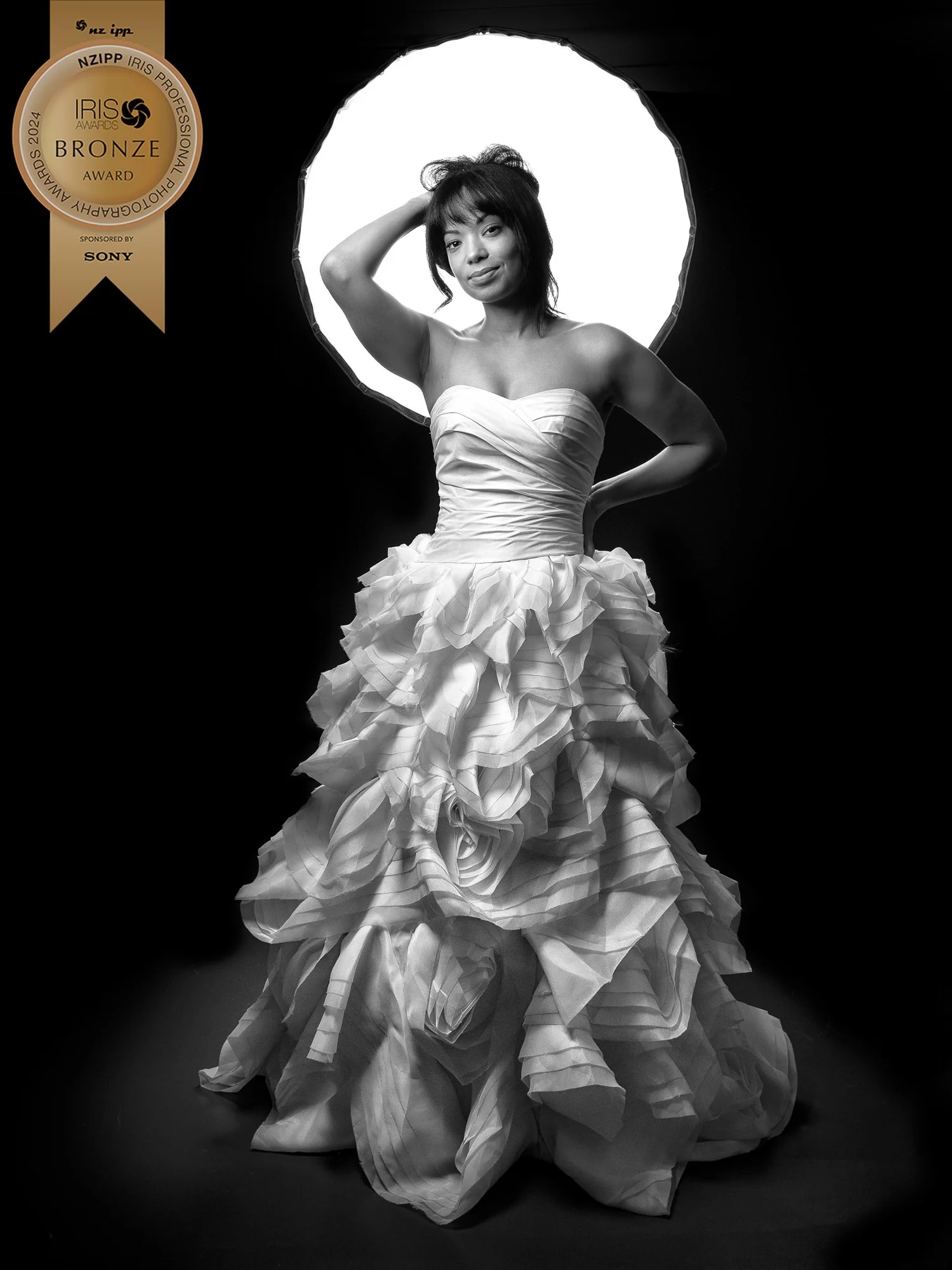 Award-winning portrait of a woman in a ruffled gown with a ring light behind