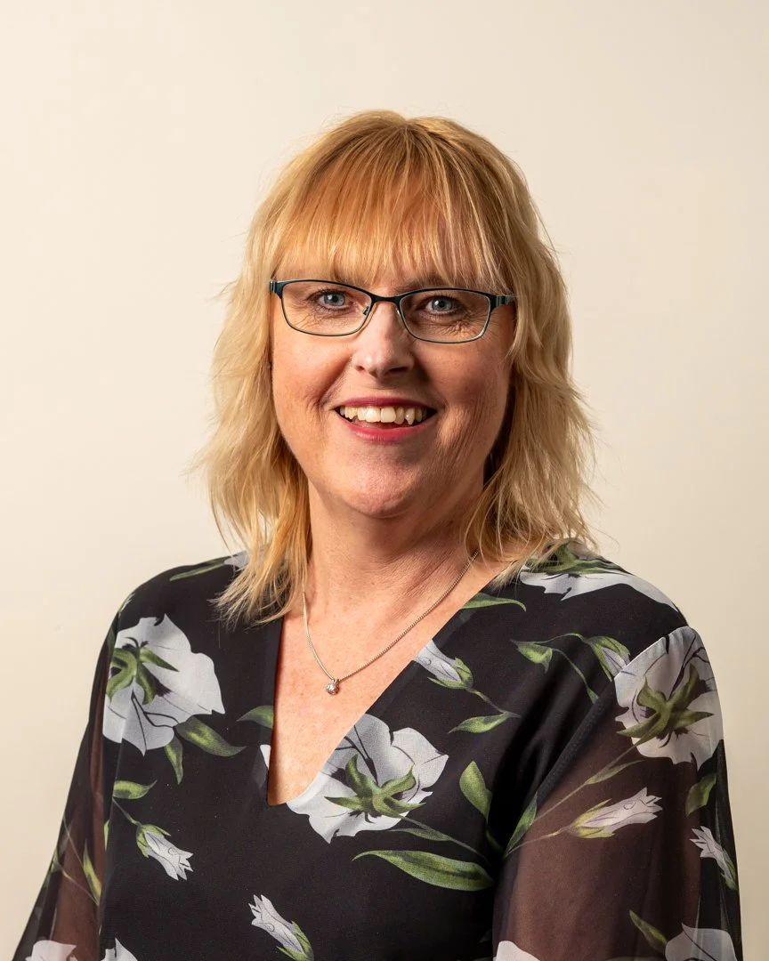 A smiling headshot of a woman in a floral top