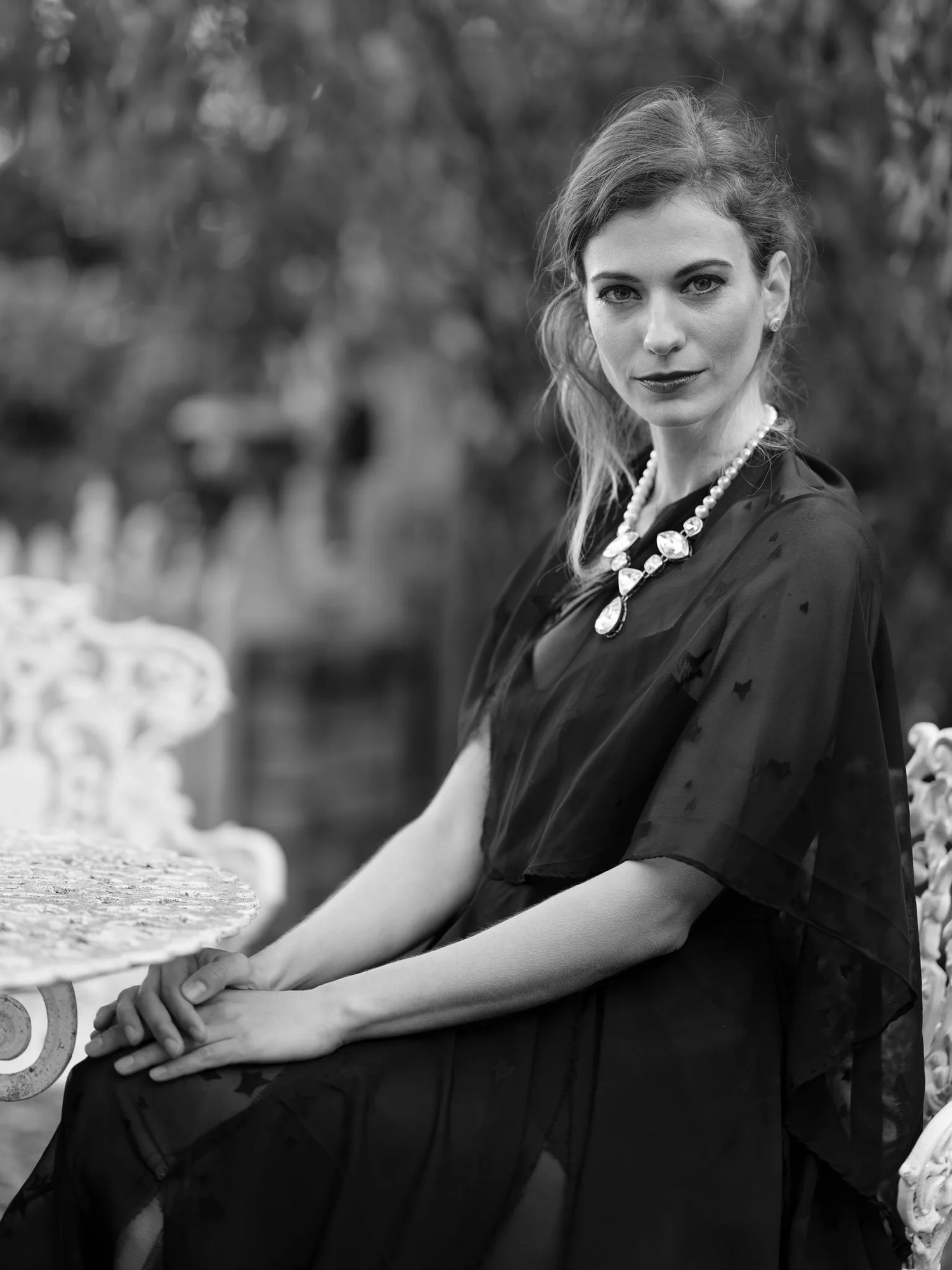 Black and white photo of a woman in a statement necklace seated outdoors