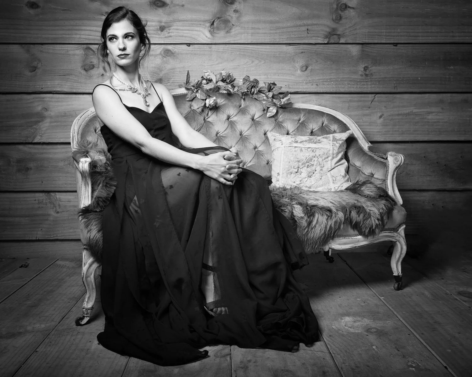 Black and white photo of a woman seated on an ornate sofa