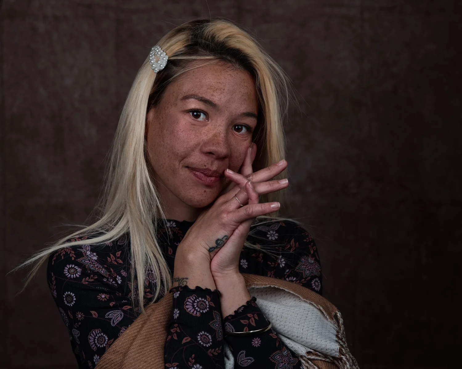 A woman with long blonde hair resting her face on her hands