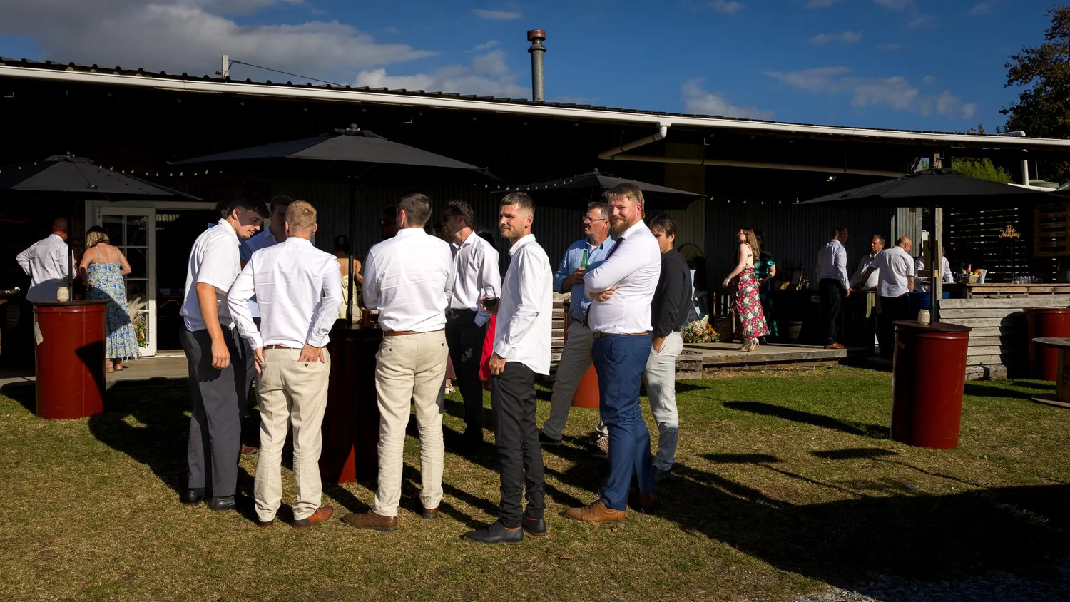 Groomsmen chat on the lawn outside the barn