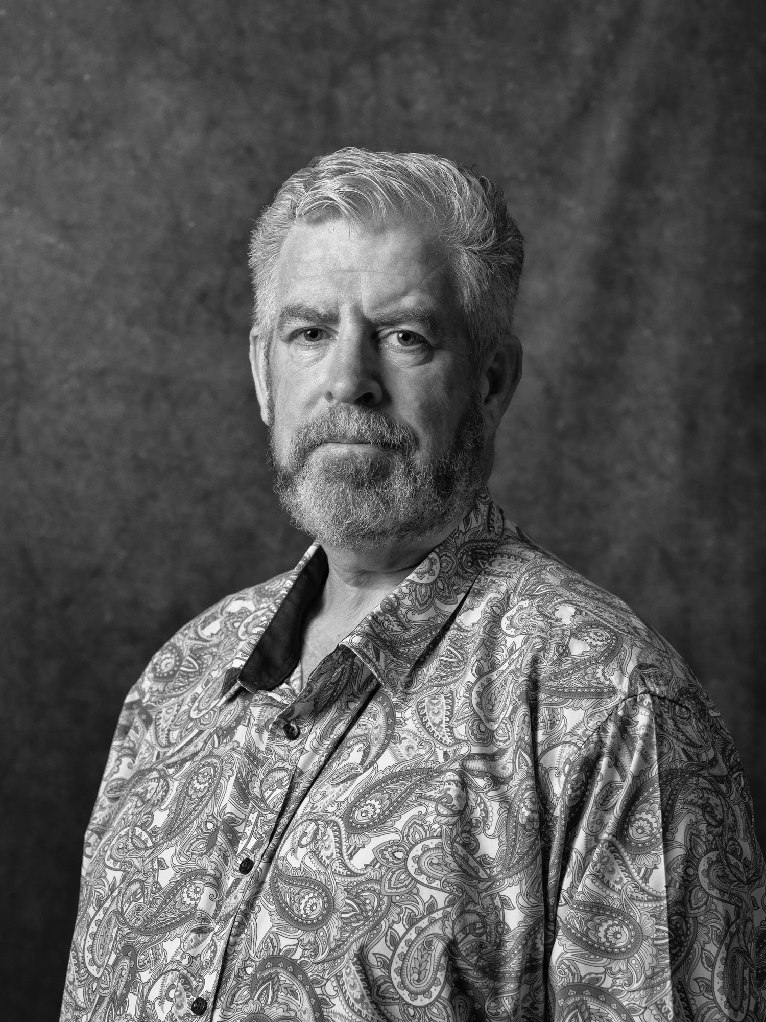Black and white headshot of a man in a paisley shirt