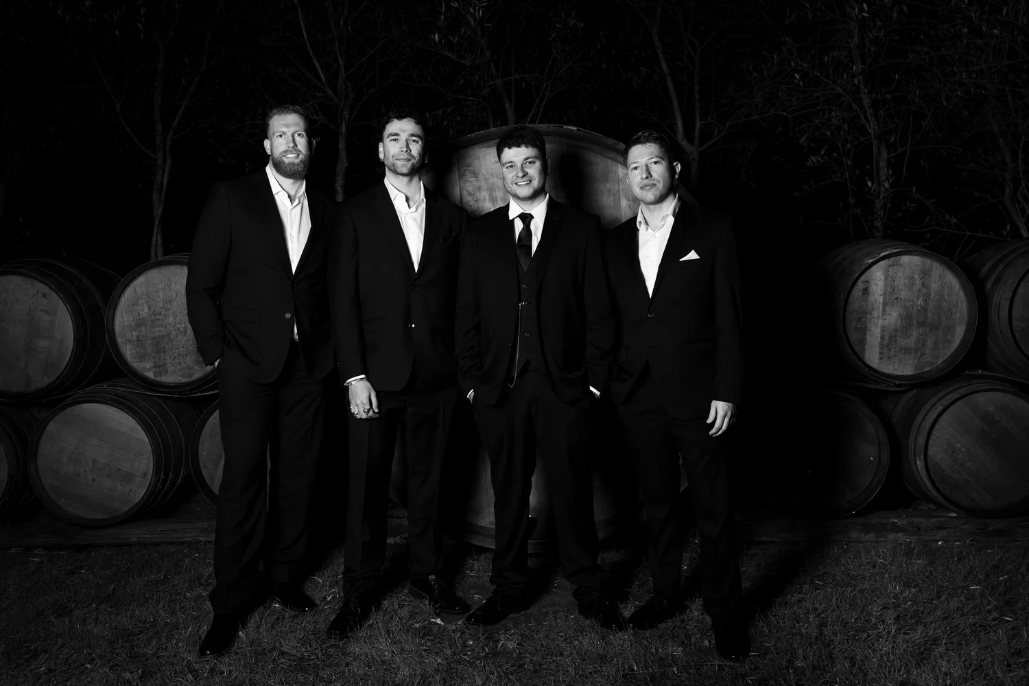 Black and white photo of the groomsmen among wine barrels
