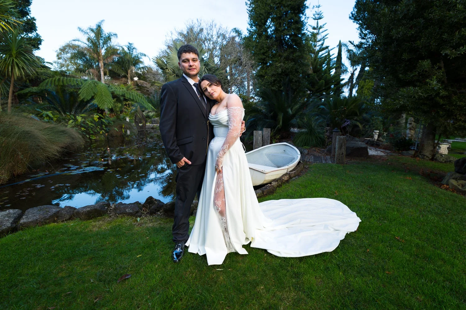 A couple pose on the lawn beside the pond