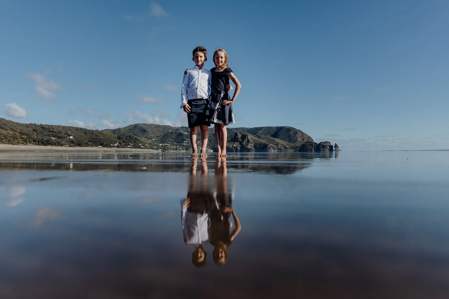 Two children reflected in the wet sand at the beach