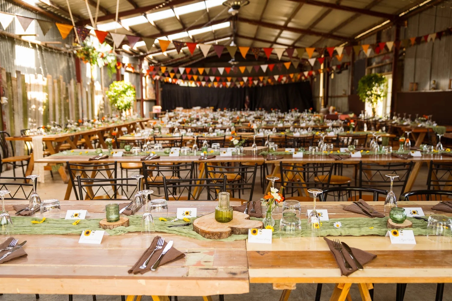 Long timber reception tables under bunting inside the barn