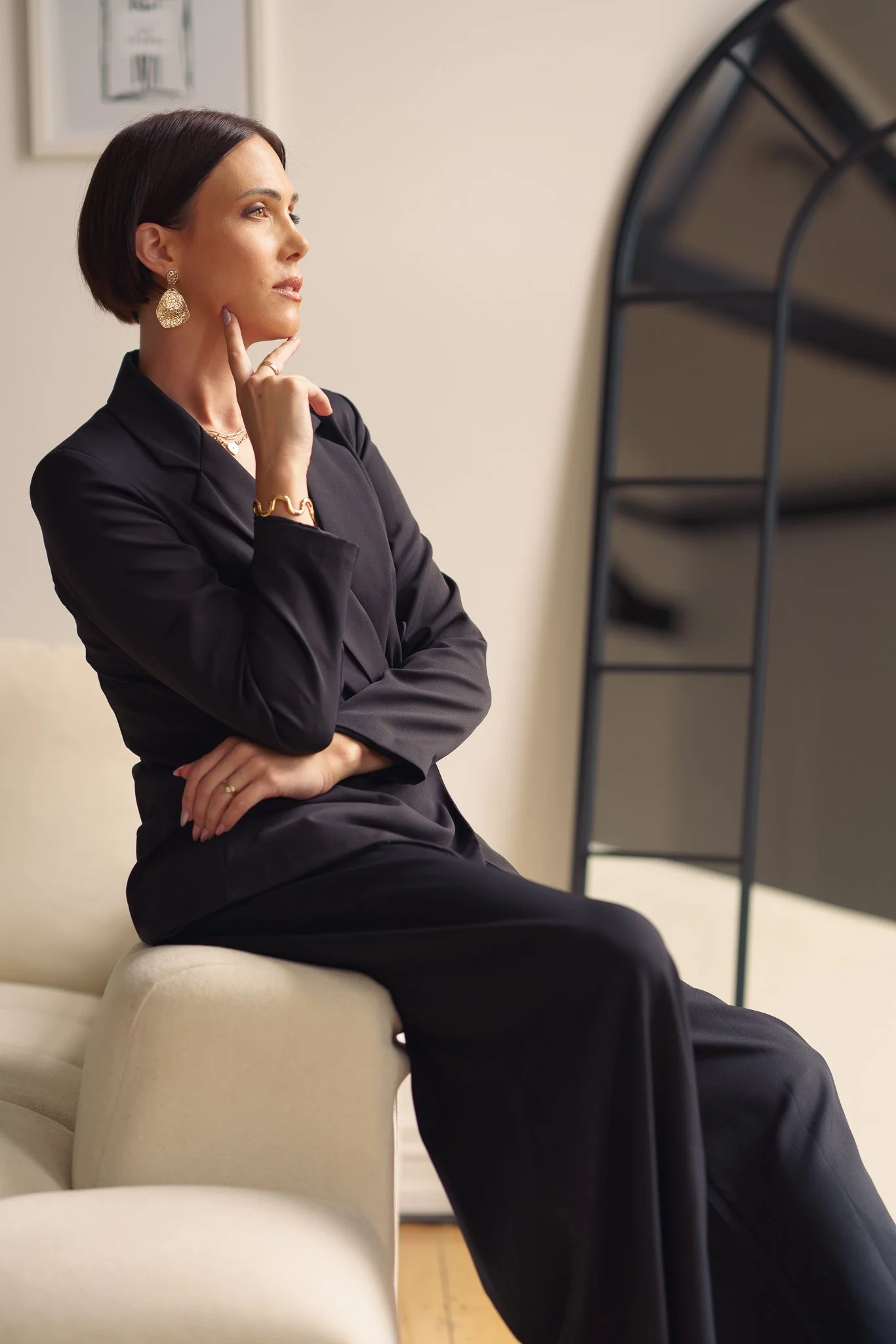 A woman in a black suit resting her chin on her hand