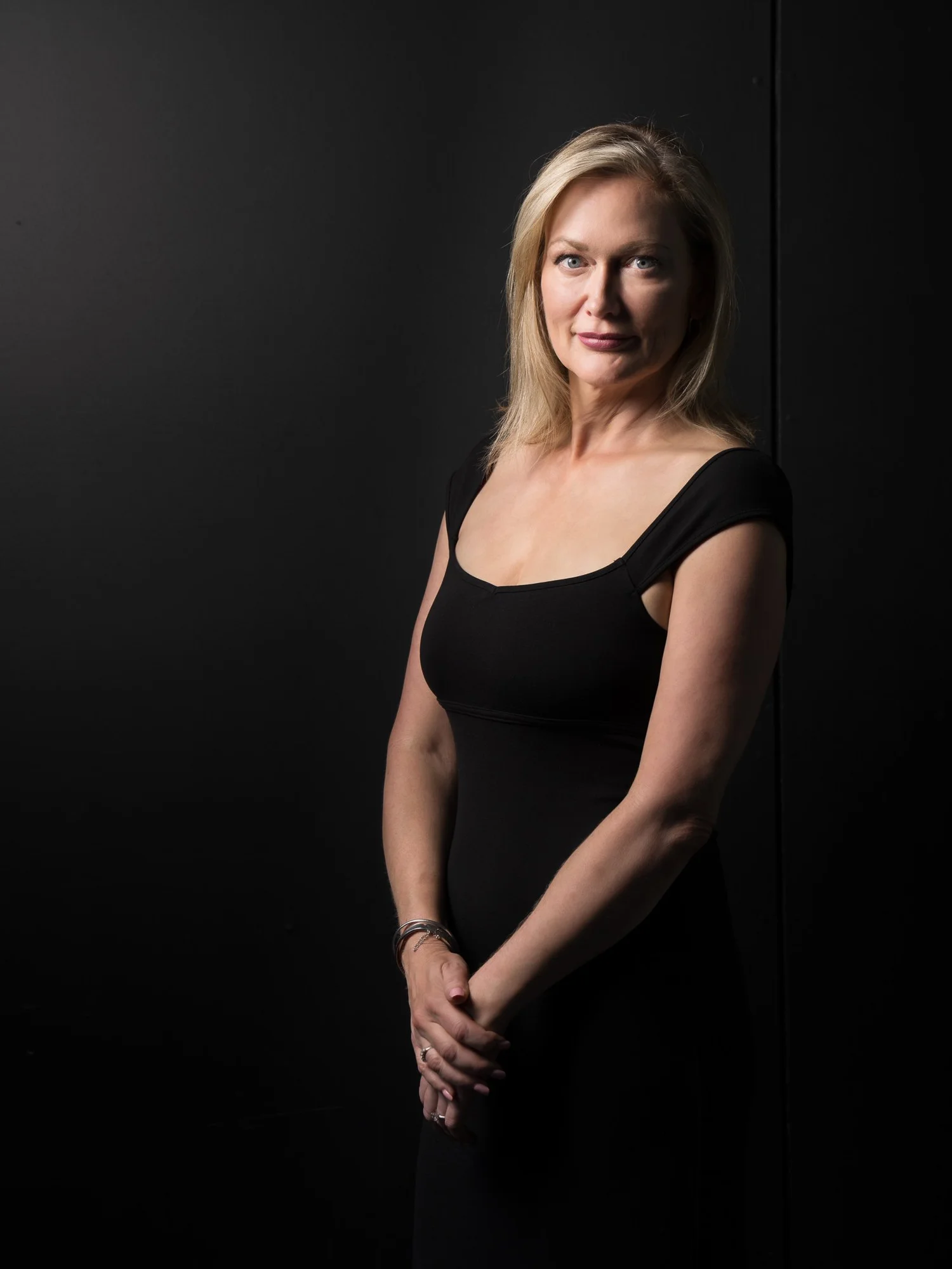 A woman in a black dress in a low-key studio portrait
