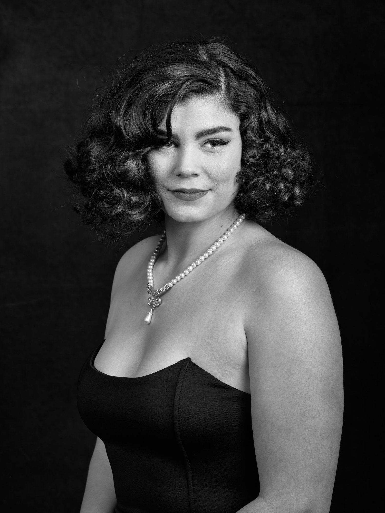 Black and white portrait of a woman with vintage curls and pearls