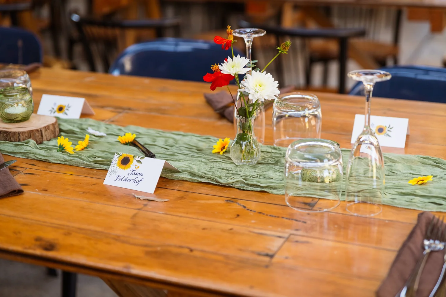 A timber table decorated with sunflowers and a green runner