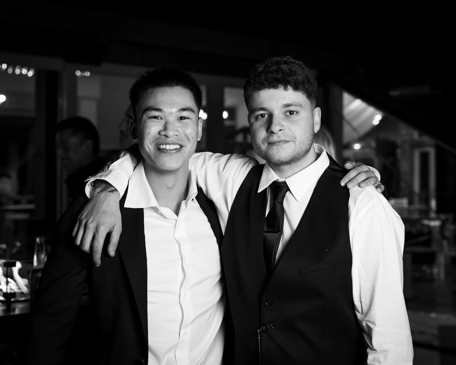 Black and white photo of two guests with arms around each other