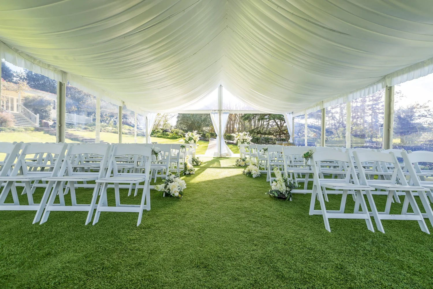 Rows of white chairs on the lawn under the ceremony marquee