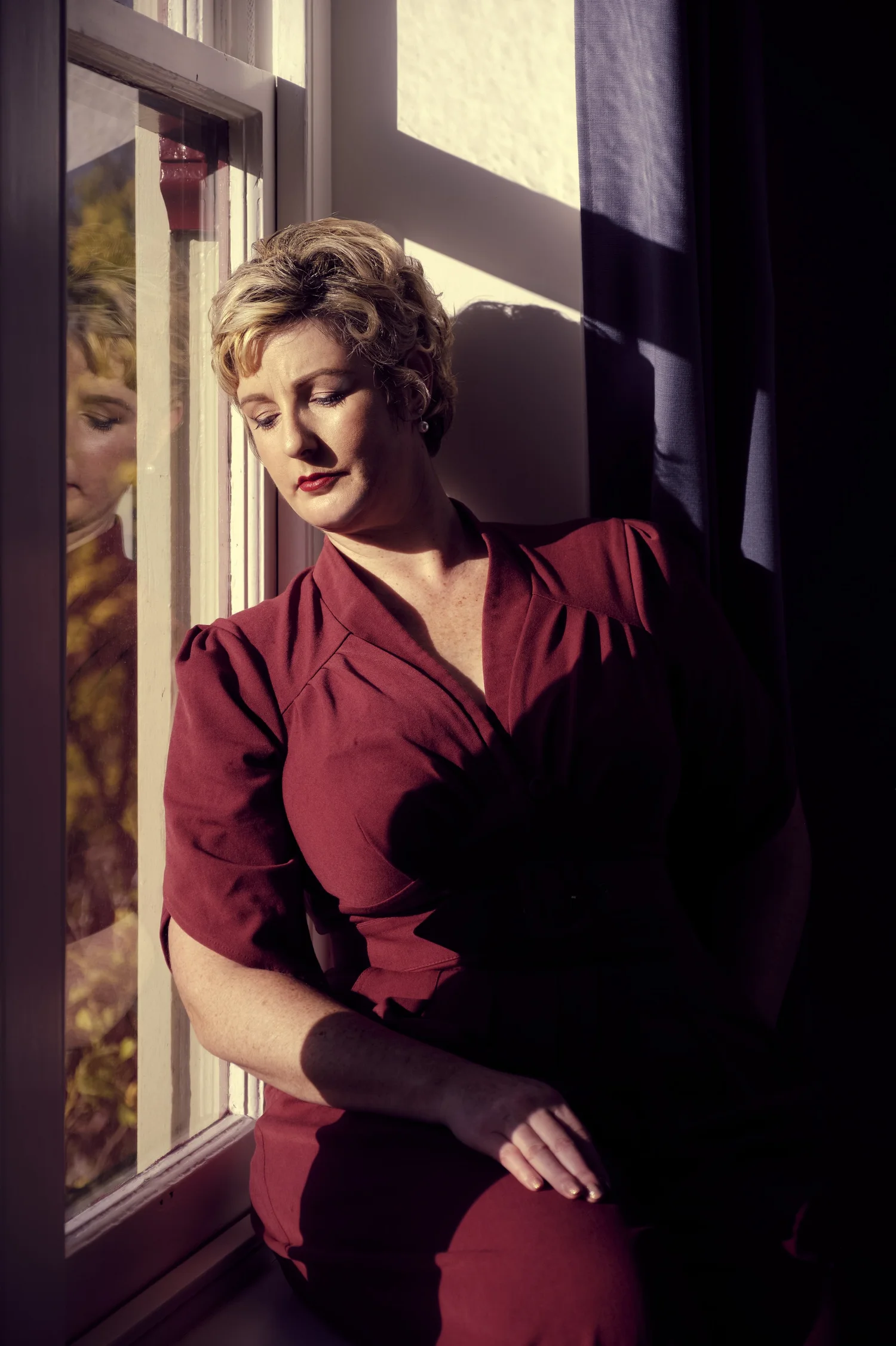 A woman in a red outfit seated by a window
