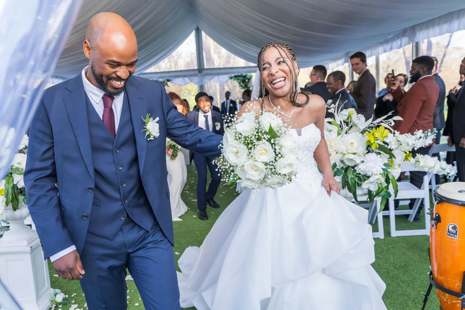 Chiedza and Foster celebrate walking up the aisle in the marquee at Abel Estate