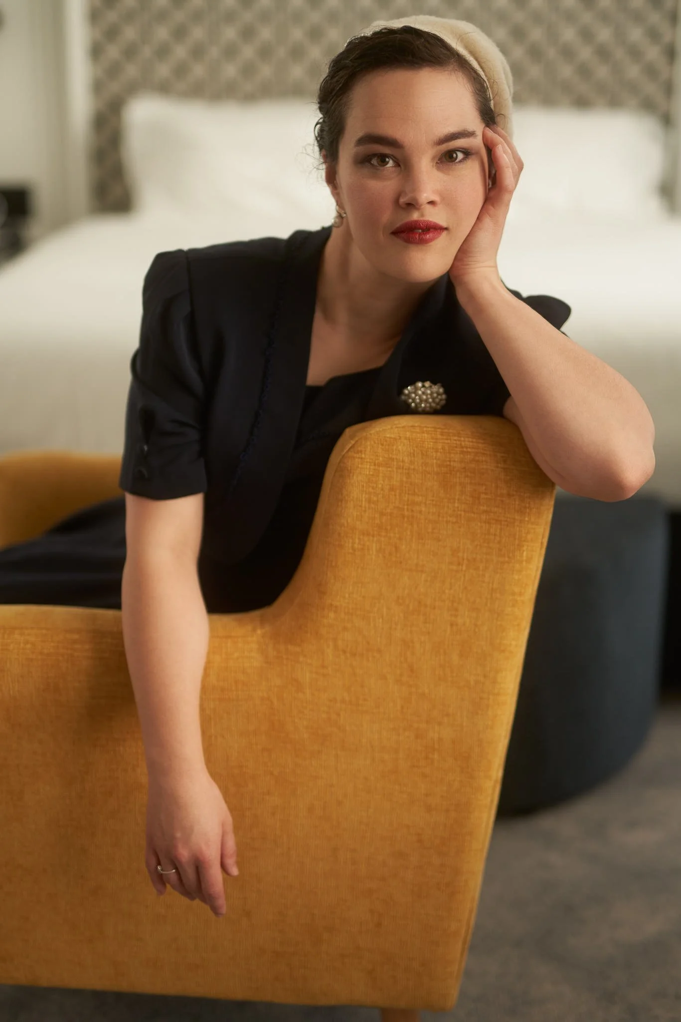 A woman in black leaning on a mustard chair