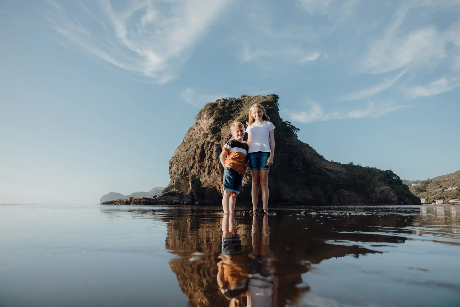 A family beside Lion Rock at Piha