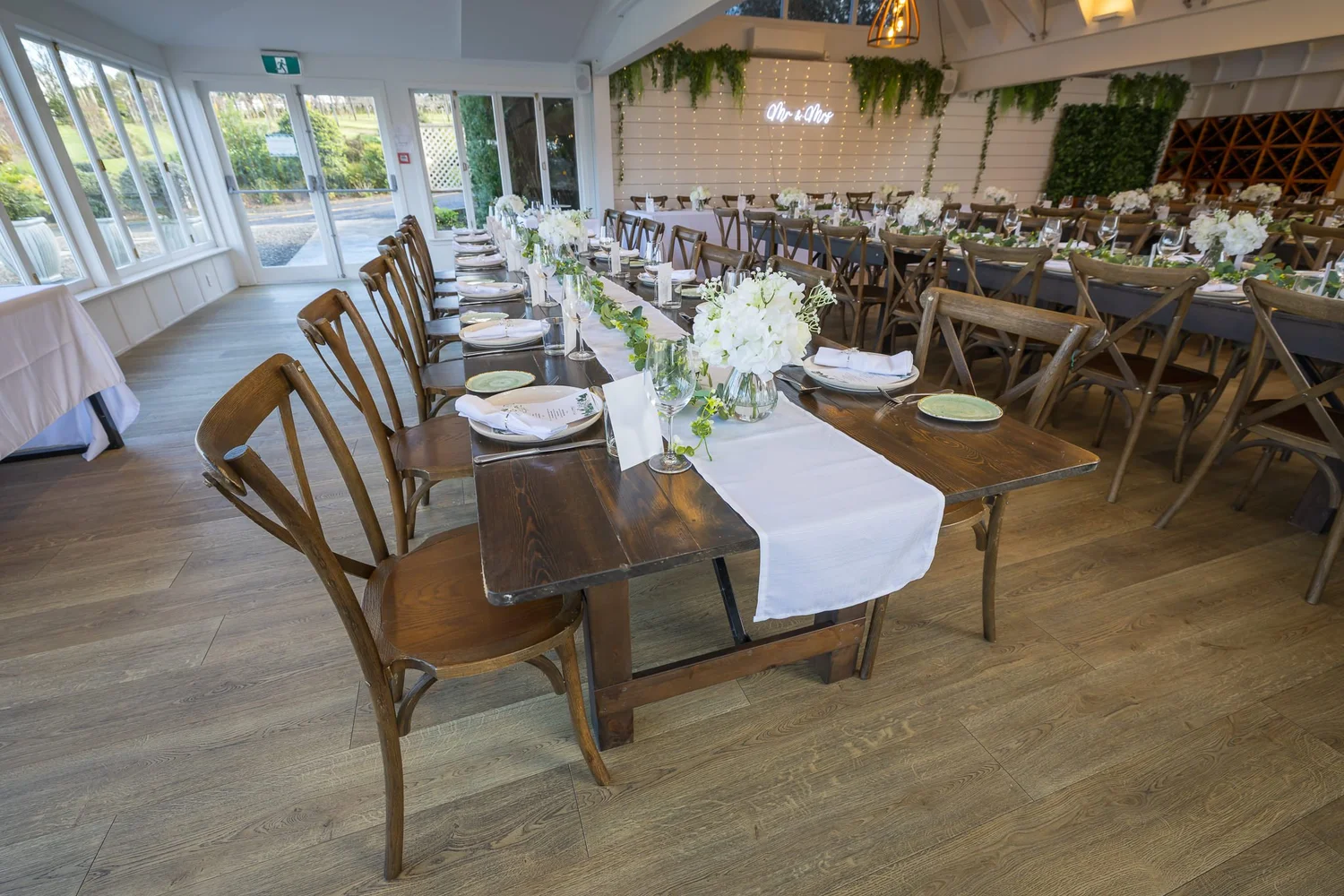 Wooden reception tables with white runners and flowers