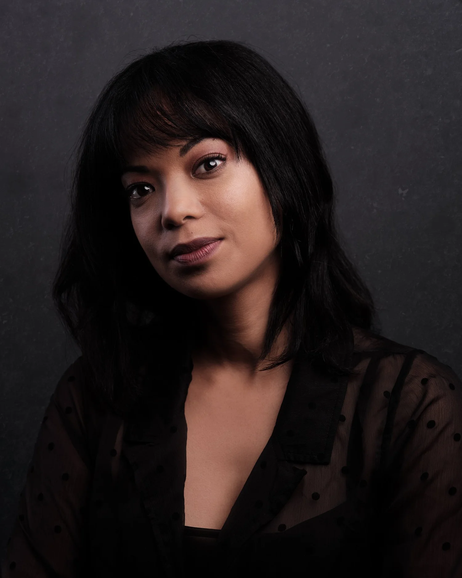 Studio portrait of a woman with dark hair and a fringe