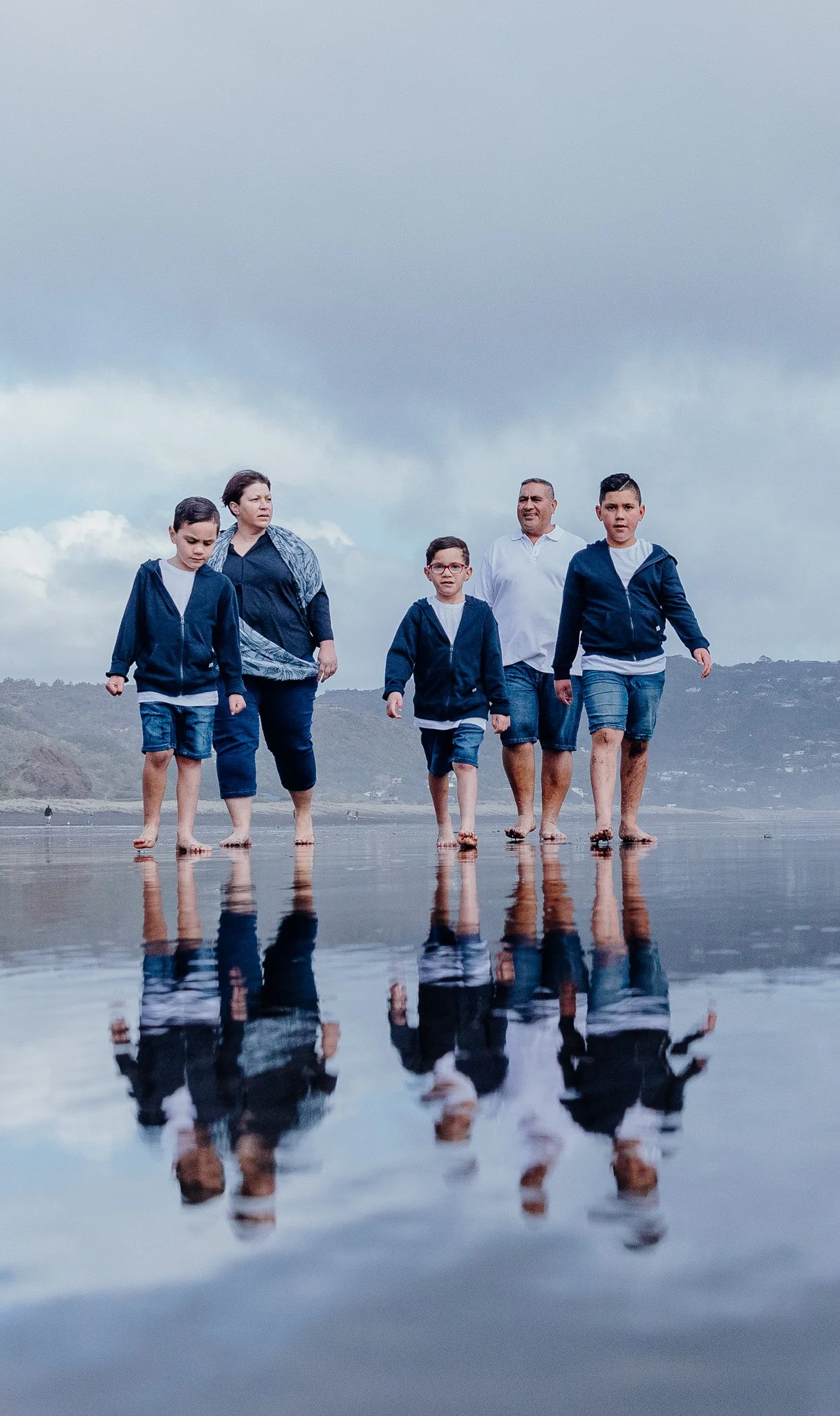 A family walking across the wet sand with reflections below