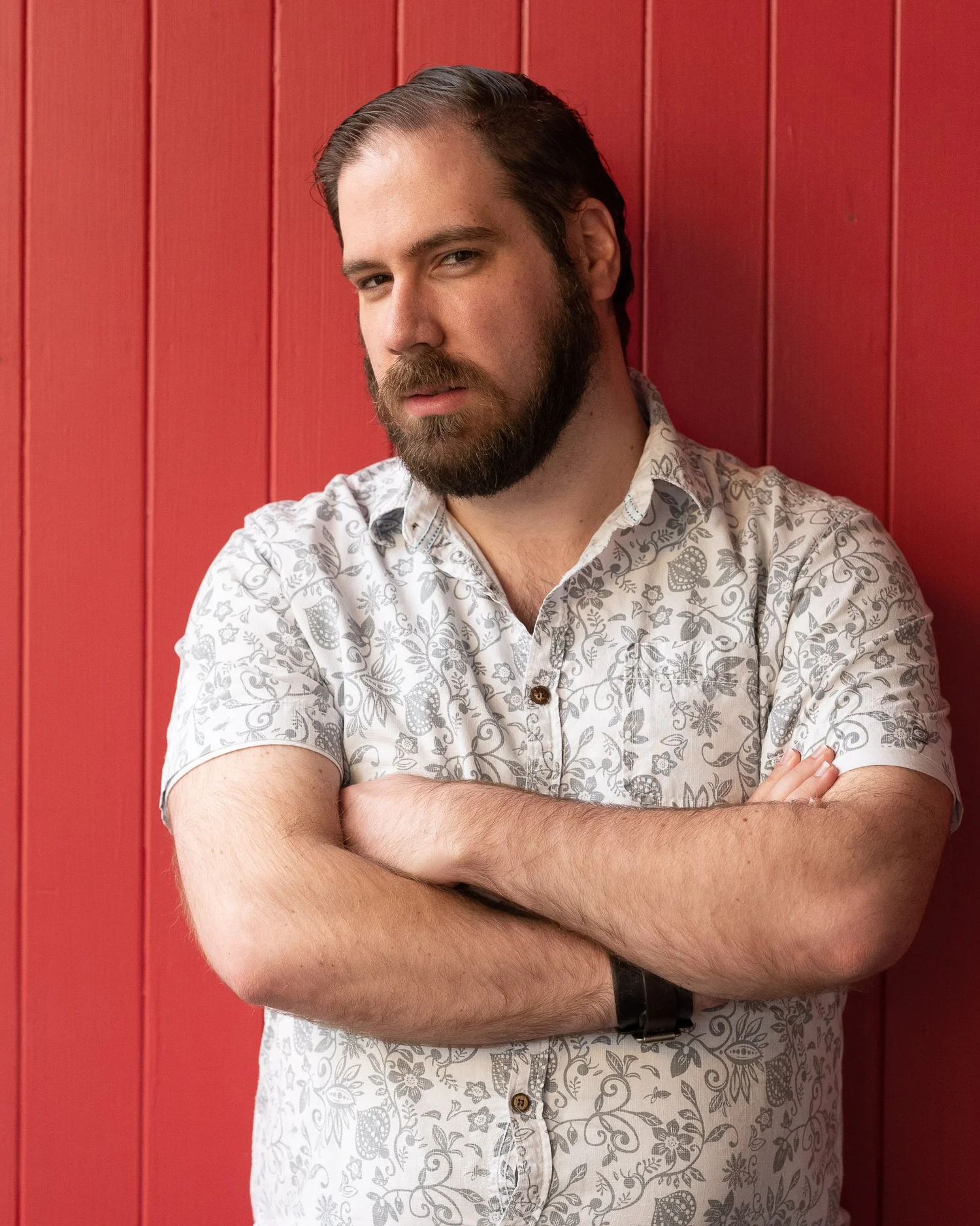 A man with folded arms against a red wall