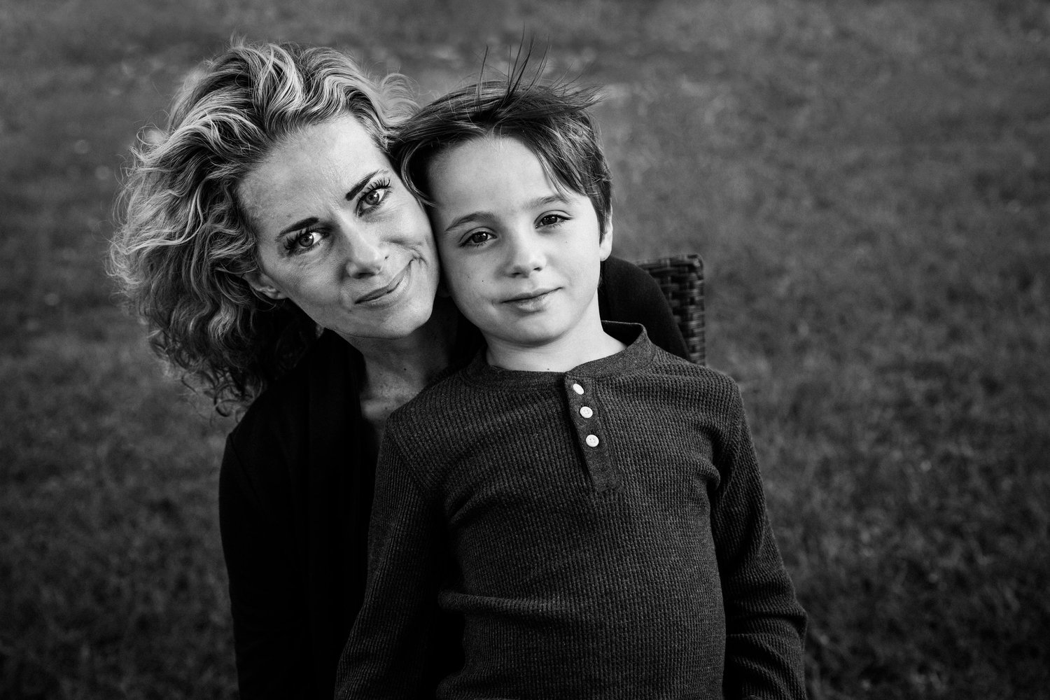 Black and white photo of a mother and son cheek to cheek