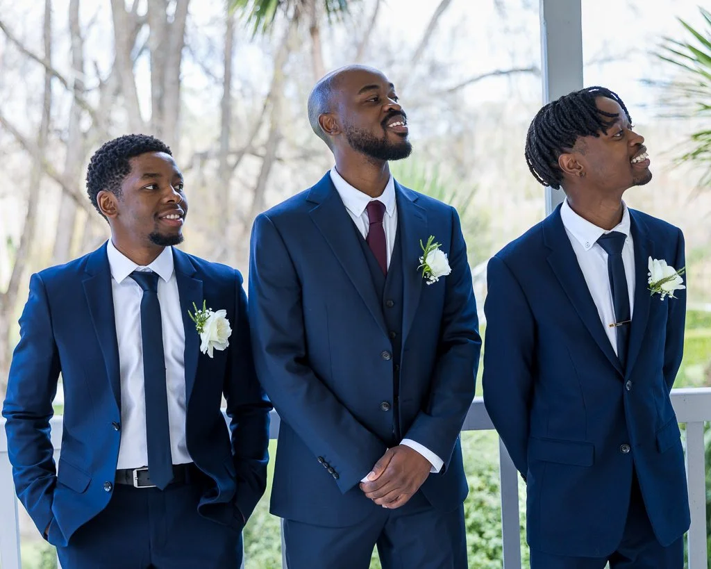 Three groomsmen in navy suits share a laugh at an Auckland wedding