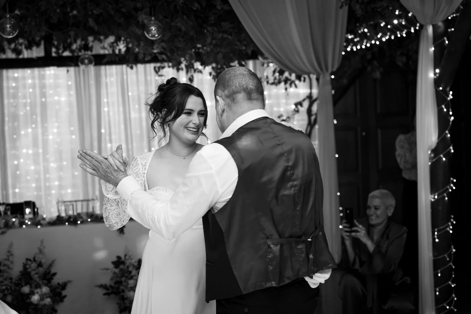 Black and white photo of the bride clapping during the speeches
