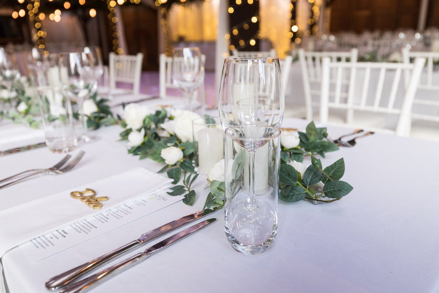 A table setting with greenery and white roses